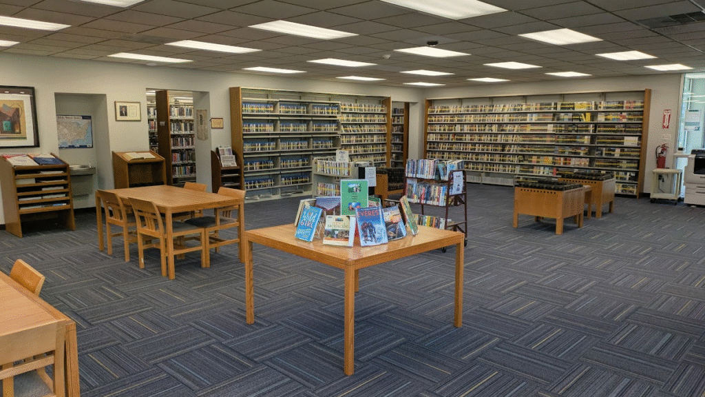 The inside of William F. Delaney Headquarters Library, with reading chairs, tables, and a book display.