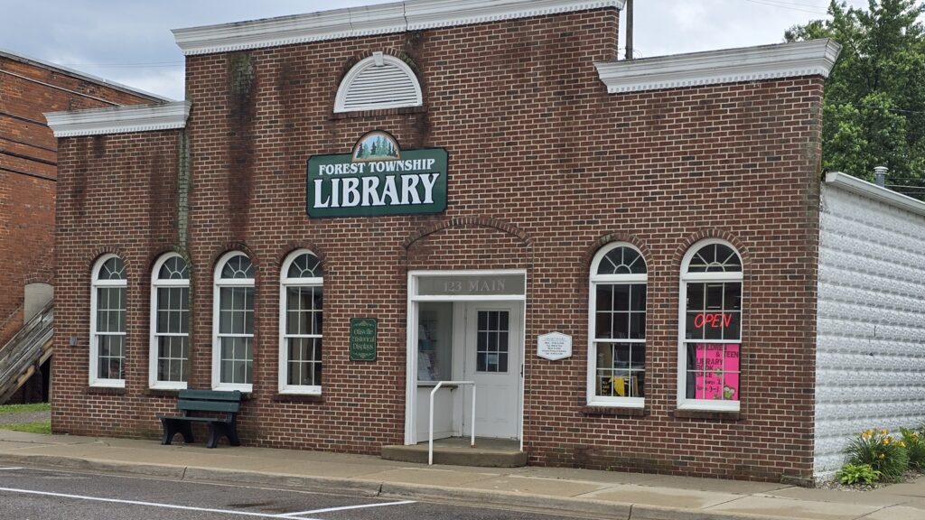 Outside view of the Forest Township Library, with a bench outside