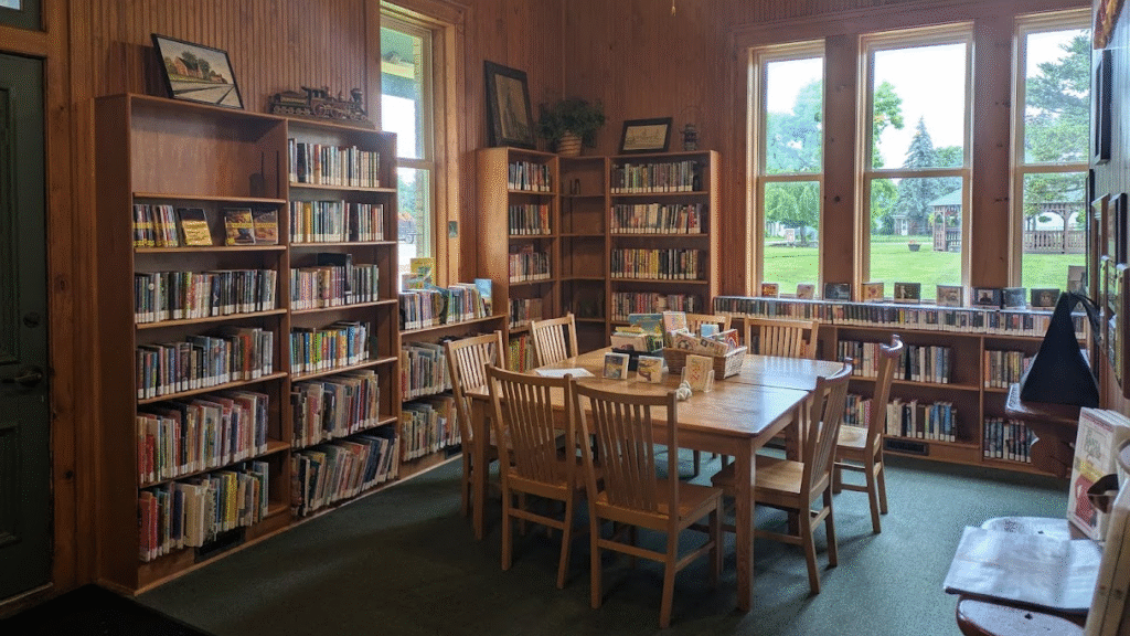 The inside of Gaines Station Library, with shelves of books and DVDs and a large table with eight chairs.