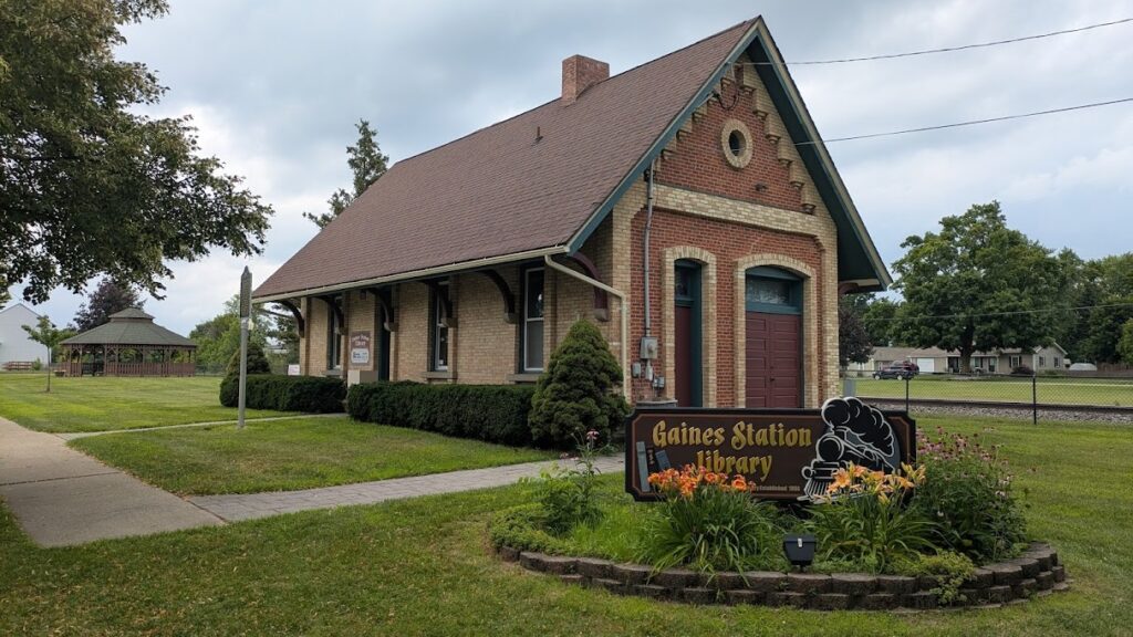 A building with a sign that says Gaines Station Library with a picture of a train