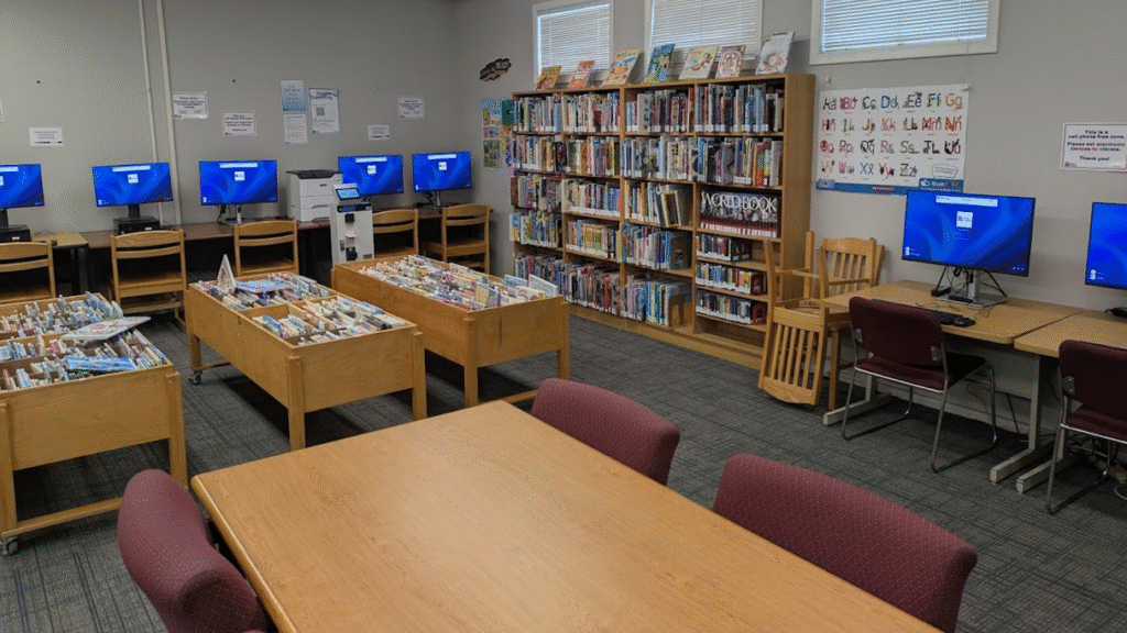 A room with a table, desks with public computers, and shelves full of books