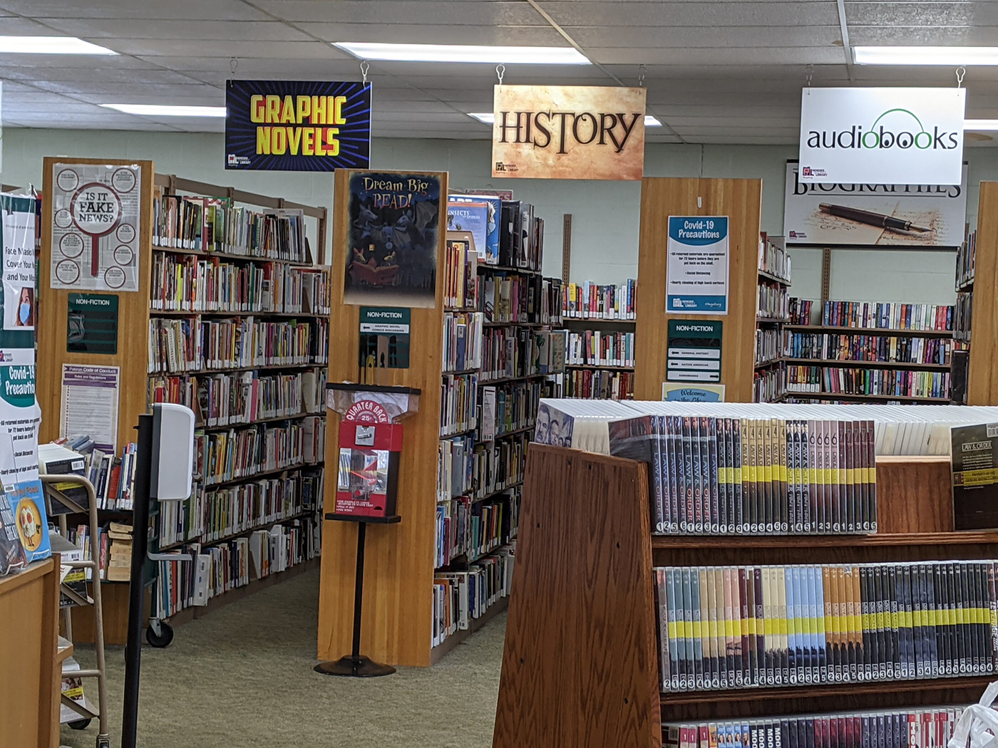 Baker Park Library shelves with Signs for Graphic Novels, History and Audiobooks